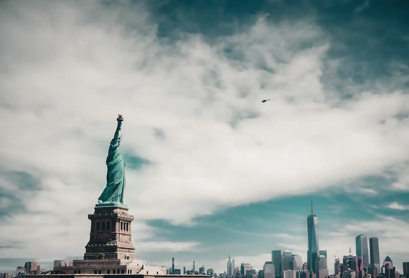 Blick auf die Freiheitsstatue von der Seite mit Skyline von New York im Hintergrund.