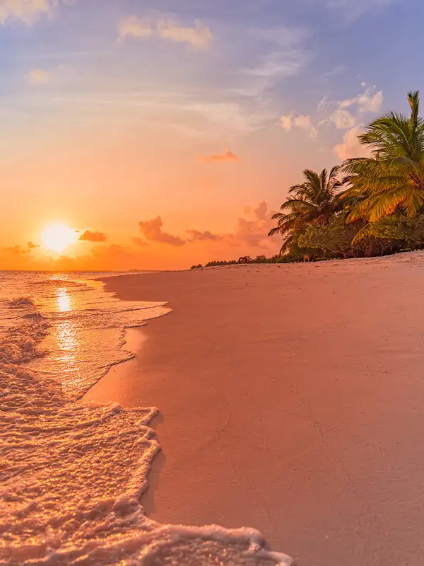 Karibische Inselstrandlandschaft mit ruhigen Meereswellen bei orangefarbenem Sonnenuntergang