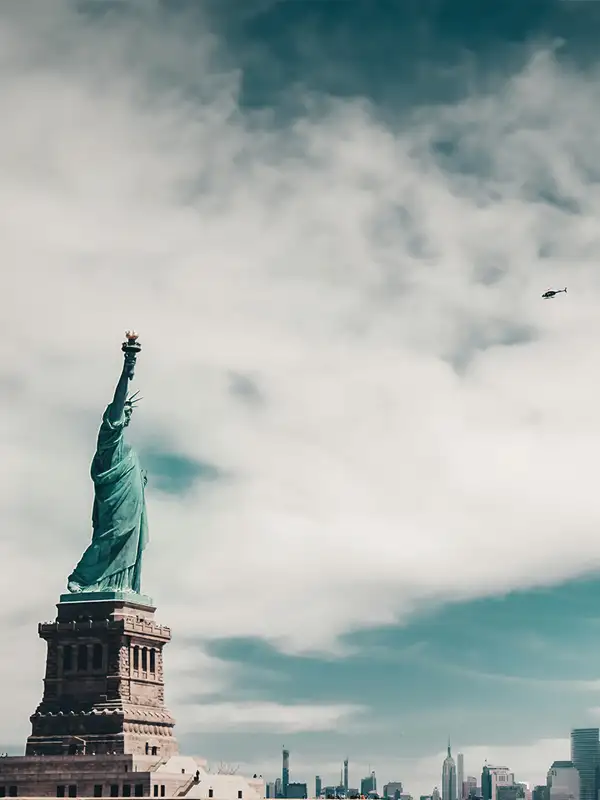 Blick auf die Freiheitsstatue von der Seite mit Skyline von New York im Hintergrund.